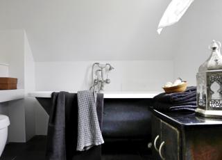 BAD MED PERSONLIGHET: De m�rkegr�, matte flisene p� baderomsgulvet danner en flott bakgrunn for badekaret med l�vef�tter. Flisene er fra Odorico.  Det vakre, gamle skapet gir ogs� personlighet til rommet. FOTO: Linnea Press