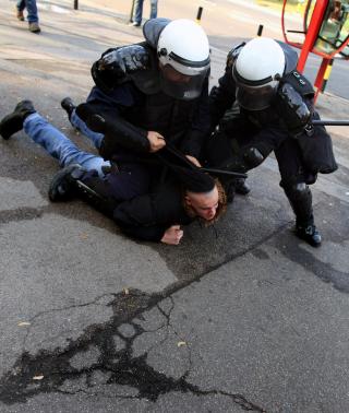 KASTET MURSTEIN OG FLASKER: Her holdes en av demonstrantene mot homseparaden nede av serbisk politi. Foto: EPA/SRDJAN SUKI