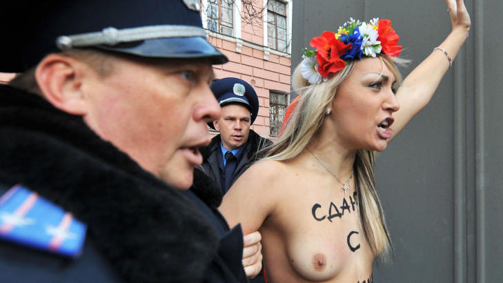 DEMONSTRERTE MOT PUTIN: Politimenn pågriper en aktivist fra Femen etter at de frivillig kom til en politistasjon i Kiev i protest mot Russlands statsminister Vladimir Putins besøk Ukraina 27. oktober. Foto: AFP Photo/Sergei Seupinsky/Scanpix
