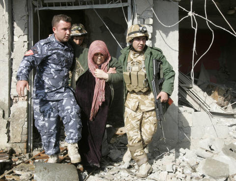 MINST 78 SKADET: Irakisk sikkerhetspersonell hjelper en kvinne like ved stedet der en av de tre bombene gikk av i Kirkuk idag. Foto: Ako Rasheed/ Reuters/Scanpix
