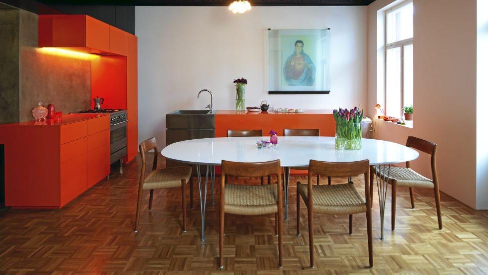 KULE KONTRASTER:  Den mandarinfargete innredningen tegnet av beboerne er laget av kunststoffet corian og mdf-plater. Brettskrurt betongvegg over arbeidsbenken. Overskap av brune forskalingsplater. Stoler kj�pt p� lauritz.com. Designbord fra Fritz Hansen. Det originale parkettgulvet ble beholdt. Elvis-bildet laget eierne selv.   FOTO: Espen Gr�nli