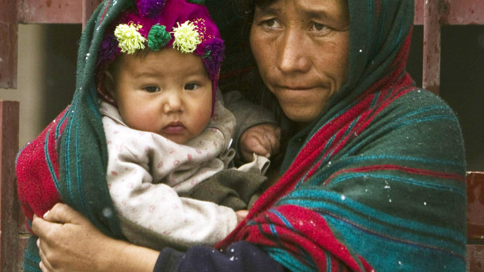 En afghansk kvinne holder ungen sin mens det sn�r i Kabul. Foto: Scanpix