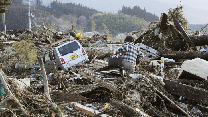 HARDT RAMMET: En beboer pr�ver � ta seg fram i de �delagte omr�dene i byen Rikuzentakata, hvor det i dag ble funnet mellom 300 og 400 omkomne. Foto: AP Photo/Kyodo News