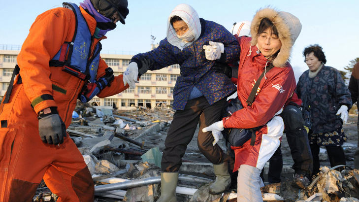 I SIKKERHET: En eldre kvinne blir hjulpet av redningspersonell i Sendai, nordøst i Japan. Foto: REUTERS/Kyodo
