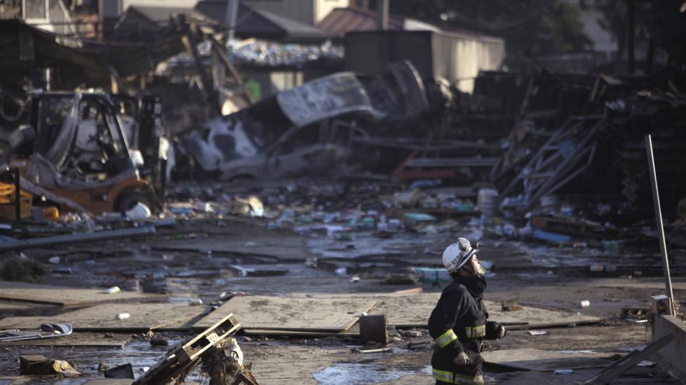I RUINER: En japansk brannmann tr�kker seg gjennom det skitne vannet i den oversv�mte byen Sendai i Japan. Foto: (SCANPIX/AP Photo/Junji Kurokawa)