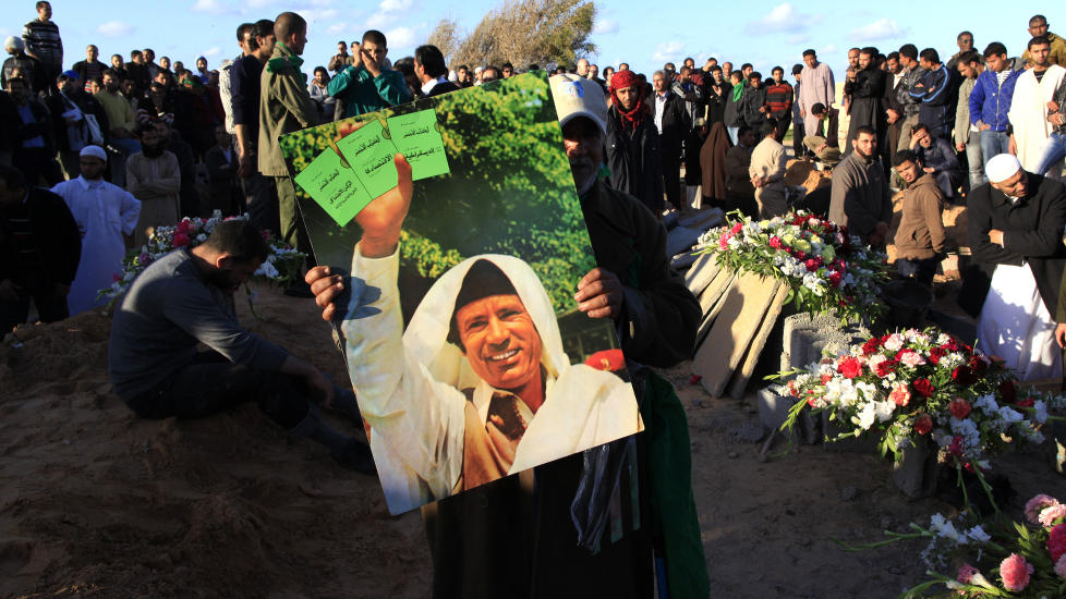 I sorg: En kvinne i Tripoli viser fram et bilde av Muammar Kadhafi under en begravelse av ofre for flyangrepene mot Libya. 
Foto: Scanpix