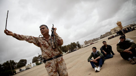 KULESKYVEREN: - Denne stanga er den som skyver ut kulene, forklarer Nouri Tawil energisk til de minst like interesserte sivile libyerne som vil ut for � bekjempe Libyas aller mest forhatte mann, Muammar Kadhafi. Foto: Tomm W. Christiansen