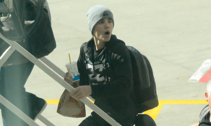 FORLATER SYDNEY: Justin Bieber med mat fra Burger King, eller Hungry Jack's som det heter i Australia, p� vei inn i flyet for � fortsette turn�en. Foto: STELLA PICTURES