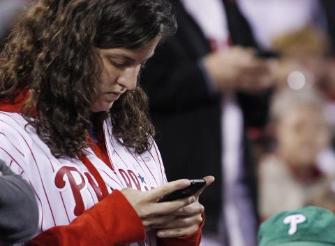 STOR AKTIVITET: Supportere sjekker mobilen underveis i kampen. Foto:  Matt Slocum, AP/Scanpix
