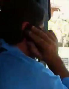 Her styrer han bussen med albuene mens han bruker to telefoner