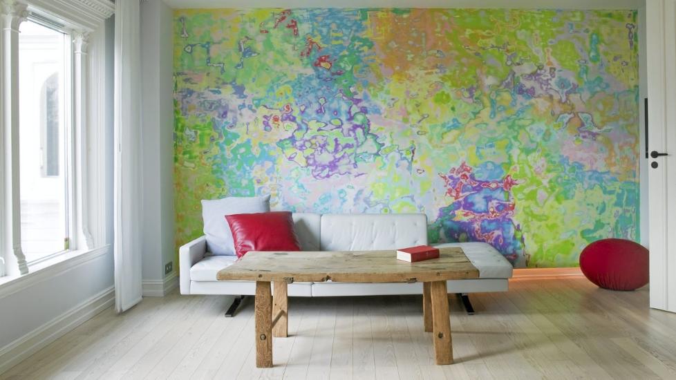 FARGER RETT P� VEGGEN: Fargerik stue med h�yst originalt veggmaleri, malt av Josefine Lyche. Gr� skinnesofa Kennedee fra Poltrona Frau og salongbord fra Loftet Antikk. R�d puff fra Tannum M�bler.  Foto: Sandra Aslaksen