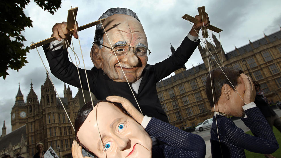 MURDOCH BESTEMMER: En demonstrant utkledd som mediemogul Rupert Murdoch gjorde narr av statsminister David Cameron og minister for kultur, media og sport, Jeremy Hunt. Foto: Adrian Dennis / AFP / Scanpix