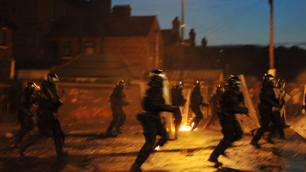 Riot police with battons run towards a crowd of Nationalist Youths during rioting which ensued after a Protestant Orange Parade in Belfast, Northern Ireland on July 12, 2011.  Trouble first flared late the day before when Protestants began lighting bonfires, the signal for the start of a day of celebrations during which thousands of Orange Order men are expected to march.   AFP PHOTO / STEPHEN WILSON