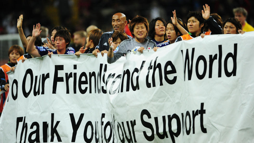 MASSE F�LELSER: Japans spillere feiret semifinale-seieren ved � ta med et stort banner p� banen. Det for � takke for st�tten etter et vanskelig �r. Foto:  AFP PHOTO / JOHANNES EISELE