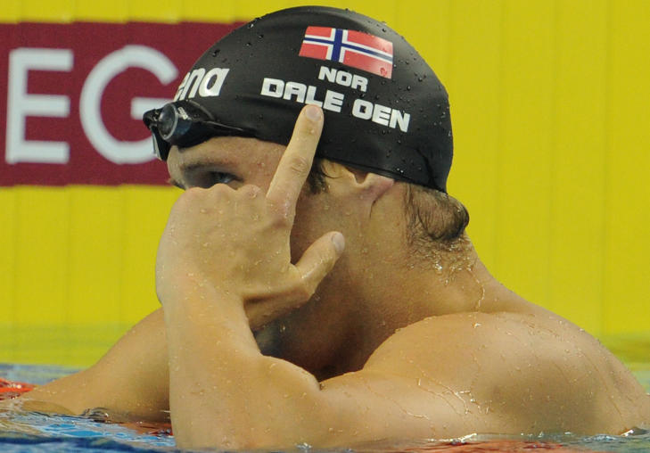 FLAGGHYLLEST: Alexander Dale Oen pekte mot det norske flagget p� badehetta etter� ha sl�tt inn til VM-gull p� 100 meter bryst. Foto: SCANPIX / AFP PHOTO / MARK RALSTON