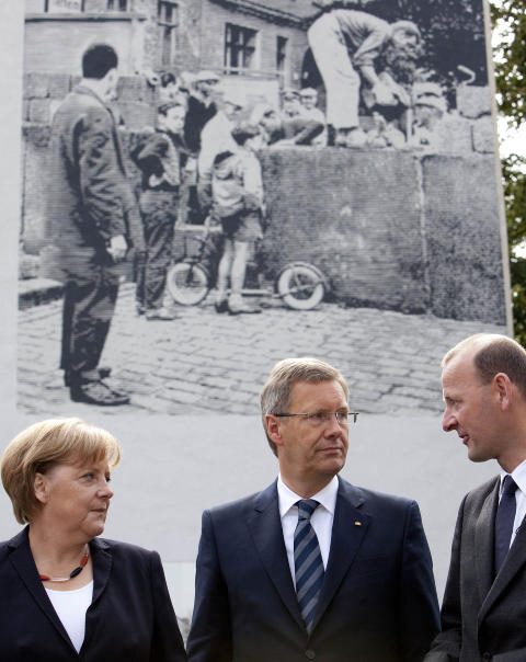 MUREN BLE VELTET: - Muren falt ikke, den ble veltet, sier Tysklands president  Christian Wulff . Her flankert av Angela Merkel og Axel Klausmeier, som er sjef for Berlinmurens stiftelse. Foto: Scanpix/AFP