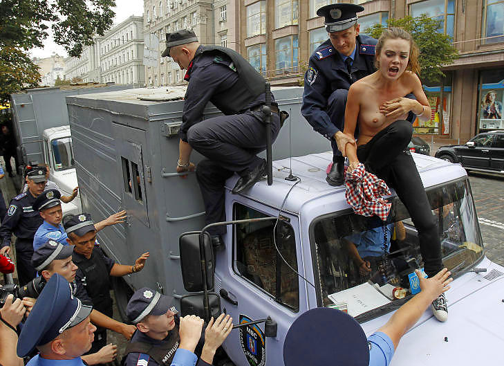 ARRESTERT: Politimenn p�griper en aktivist fra kvinnegruppa Femen som har klatret opp p� taket av en politibil i den ukrainske hovedstaden Kiev idag. Foto: Gleb Garanich / Reuters / Scanpix