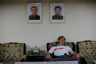 SLAPPER AV: Et medlem av den kinesiske turistdelegasjonen sover under bildene av Nord-Koreas leder Kim Jong-II og hans avd�de far Kim II-Sung.  Foto: CARLOS BARRIA/REUTERS/SCANPIX