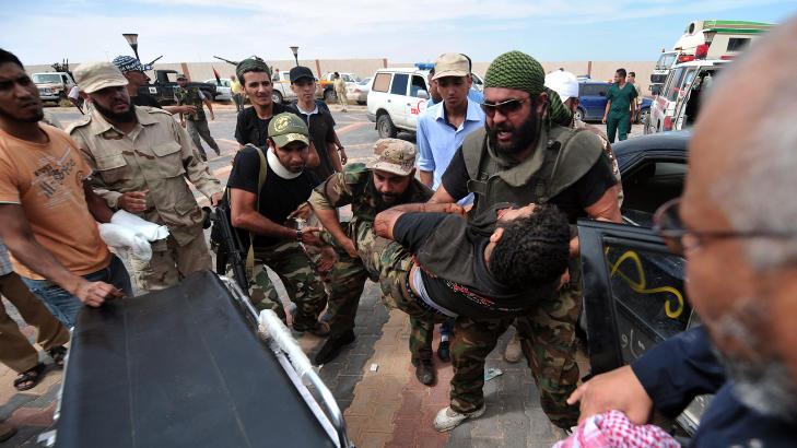 KAOS: Det er mange s�rede, og det meldes om kaotiske tilstander p� lokale sykehus. Her blir en s�ret NTC-soldat l�ftet opp p� en b�re utenfor et feltsykehus. Foto: SCANPIX/AFP PHOTO/ARIS MESSINIS