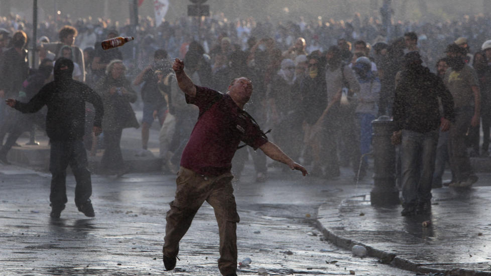 KASTET FLASKER: Her angriper demonstranter politiet i Roma i en av mange demonstrasjoner mot politikere og banker i dag. Foto: AP/Scanpix