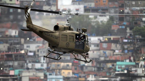 HOLDT OPPSYN: Politihelikopteret, fullt av tungt bev�pnet personell, overv�ket aksjonen i dag. Foto: AFP/Luiza Castro/Scanpix