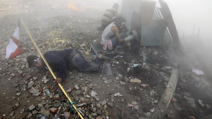 T�REGASS: Demonstranter g�r her i dekning n�r politiet skyter t�regass mot dem. Foto: SCANPIX/REUTERS/GORAN TOMASEVIC