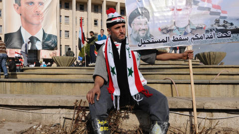 ST�TTER PRESIDENT: En tilhenger av Syrias president Bashar al-Assad holder en plakat av presidenten og Libanons Hizbollah-leder Sayyed Hassan Nasrallah. Foto: Reuters/Scanpix