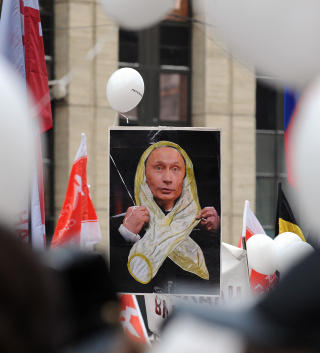KONDOM-PUTIN:  Putin gjorde narr av demonstrantenes hvite t�ystykker ved forrige demonstrasjon og sa de s� ut som kondomer. I dag fikk han smake sin egen medisin. Foto: Yuri Kochetkov / EPA