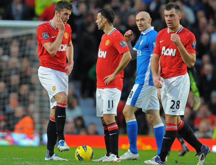 STRENG UTVISNING: Conor Sammon (bak) kj�rte en h�nd opp i ansiktet p� Michael Carrick (t.v.). Det resulterte i et strengt r�dt kort og en tiln�rmet umulig oppgave for Wigan.Foto: SCANPIX/AFP PHOTO/ANDREW YATES