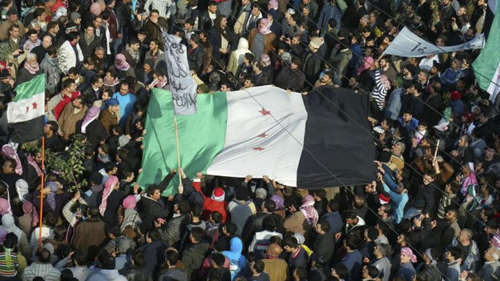 DEMONSTRASJONER I FLERE BYER: Demonstranter veiver med flagg og roper slagord i Abld i Syria fredag 30. desember. Foto: REUTERS/Handout