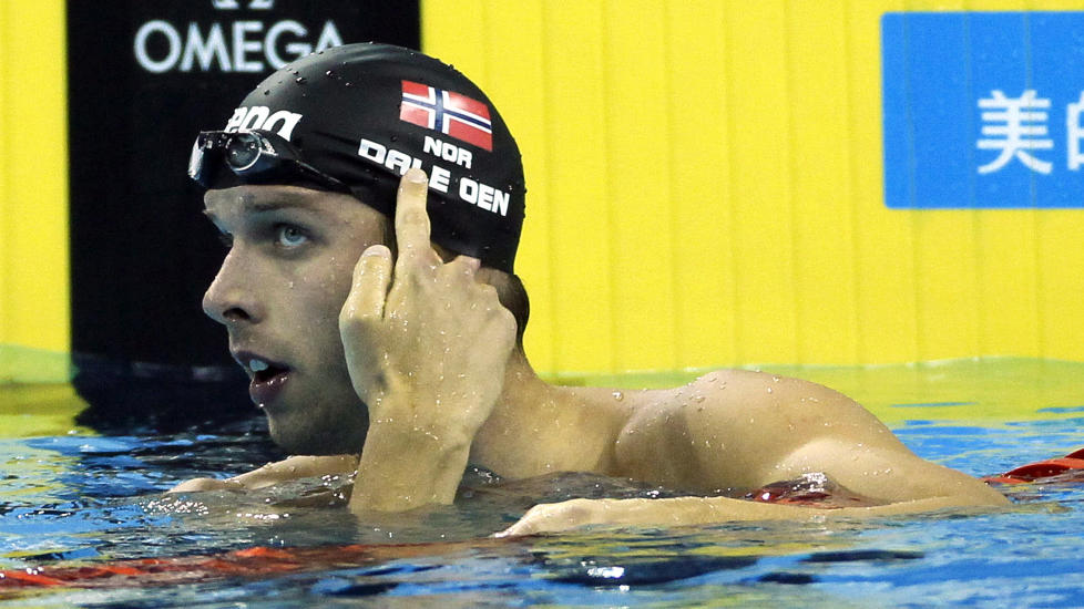 STERKE F�LELSER: Alexander Dale Oen vant VM-gull p� 100 meter bryst i Kina 24 juli. Han markerte at tankene var like mye p� det som skjedde i hjemlandet ved � peke p� flagget p� badehetta rett etter m�lgang. Foto: Eugene Hoshiko, AP/Scanpix