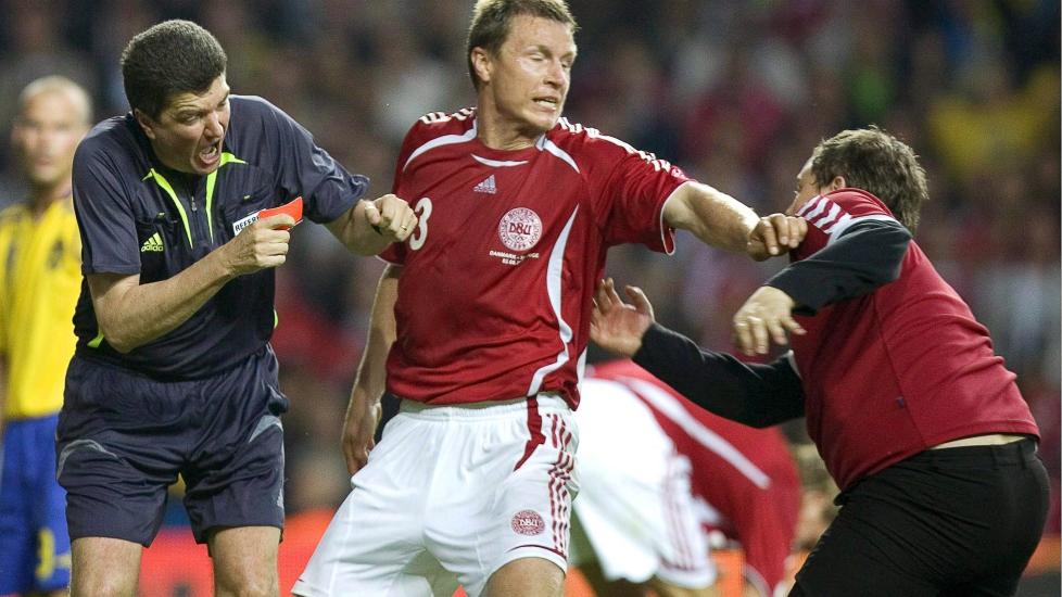 BESKYTTET DOMMEREN: Det danske fotballfjolset rakk s�vidt � f� inn et slag mot dommer Herbert Fandel f�r Michael Gravgaard stanset ham. N� synes den danske midtstopperen synd p� overfalleren. Foto: EPA/ANDERS WIKLUND