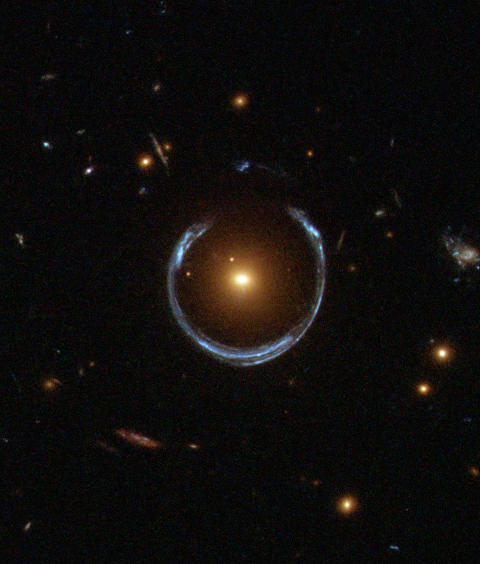 FORVRIDD: Et eksempel p� sterk gravitasjonslinsing. Den gule galaksen i sentrum av bildet forst�rrer og b�yer lyset fra den bl� galaksen i bakgrunnen til en stor ring. Les mer om bildet p� NASAs hjemmesider. Foto: ESA/Hubble/NASA