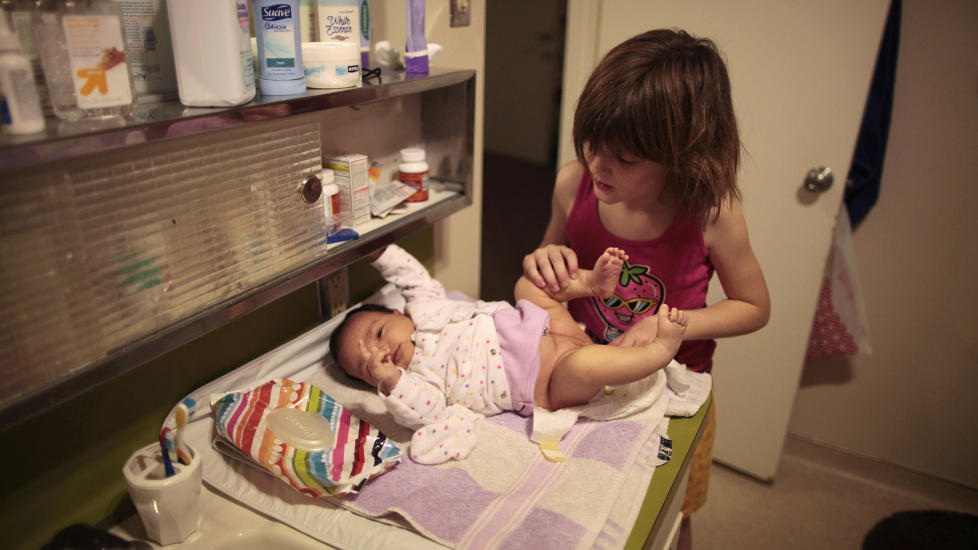 IKKE EGET HJEM:  If�lge National Center of Famliy Homelessness er totalt 1,6 millioner amerikanske barn hjeml�se i USA. Lilly Earp (8) skifter bleie p� sin fire uker gamle s�ster, Emily, p� et senter for hjeml�se kvinner og barn organisert av Union Rescue Mission, utenfor Los Angeles i California. De bodde p� hotell i en m�ned f�r moren fikk plass p� senteret. Foto: Lucy Nicholson / Reuters / Scanpix