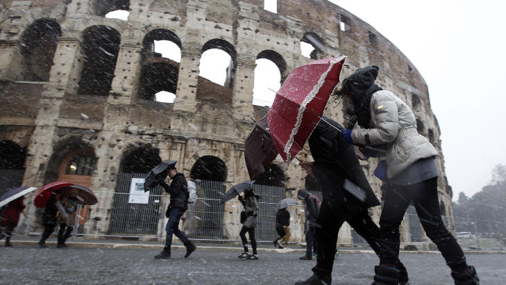VINTERPREG(O): Roma-turister fors�ker � beskytte seg mot vind og sn� ved Colosseum. Foto: REUTERS/Alessandro Bianchi/SCANPIX