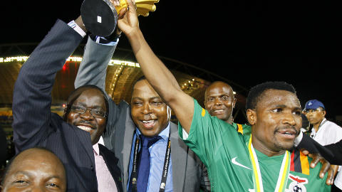 SYMBOL: Fotballpresident Kalusha Bwalya (bl�tt slips) med h�nda p� trofeet sammen med kaptein Christopher Katongo/AP/Francois Mori