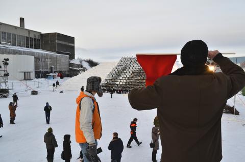 LEDET MASSENE: Arirang-instrukt�ren Ri Gwang Nam dirigerte det levende bildet fra en sn�haug til h�yre for sn�tribunen. Foto: Bj�rn S. Kristiansen