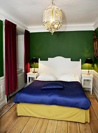 INNBYDENDE: Romslige rom med tunge gardiner, gamle tregulv og kakkelovn.