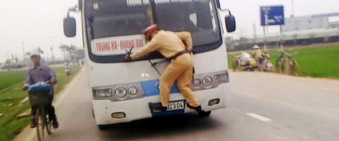 Her klamrer politimannen seg til flyktende buss