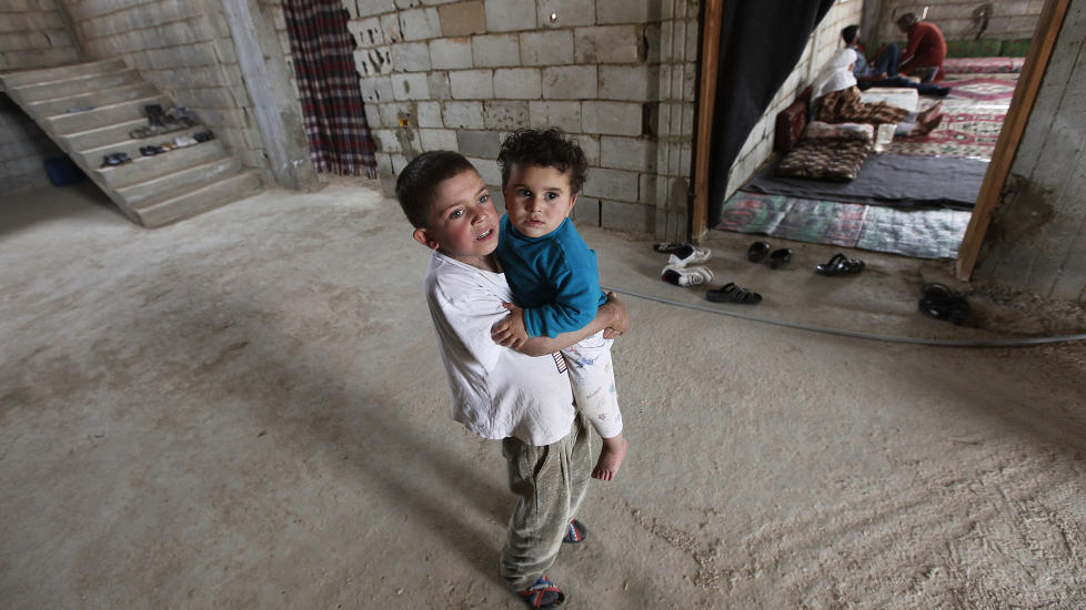 P� FLUKT: Syriske Nahar al-Nahar (9) b�rer sin slektning Mounir (18 m�neder), som har flyktet fra sine hjem i Homs.Foto: AP Photo/Hussein Malla/NTBScanpix