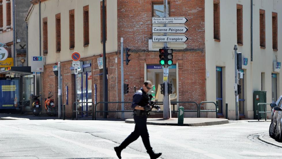  DRAMA:  En politimann l�per over gata. I bakgrunnen skimtes banken der dramaet p�g�r. Foto: AFP PHOTO / ERIC CABANIS