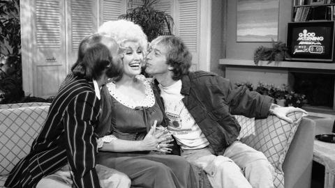 FL�RTER GJERNE: Dolly Partons ektemann blir ikke sjalu selv om hun kysser p� tv. Her er det Morris Gibb og Robin Gibb som serverer artisten kyss p� kinnet under et morgenprogram p� ABC. Foto: Mario Suraini / AP Photo / NTB Scanpix