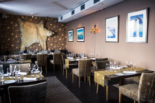 RESTAURANTEN: 
P� veggen henger et isbj�rnskinn. Den ble skutt p� kirketrappa i Longyearbyen for et par ti�r siden. Tilberedt etter alle kunstens regler ble bamsen servert p� Huset mens gjestene sang �Bj�rnen sover�. Foto: ROGER BRENDHAGEN