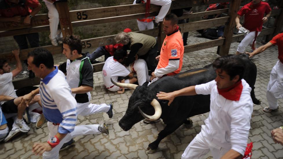 L�PER FOR LIVET Deltakere i det �rlige oksel�pet i Pamplona er her snublende n�r � f� et oksehorn i ryggen. Foto: AFP / Pedro Armestre / NTB Scanpix