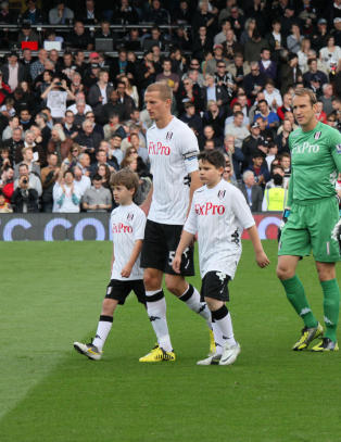 Her går han hånd i hånd med kapteinen inn på et fullsatt Craven Cottage