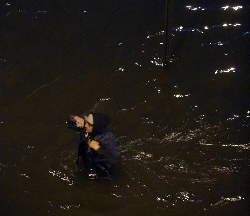 <b></b> En mann trosser advarslene om å bevege seg utendørs, og går gjennom stormfloen i en Brooklyn-gate.