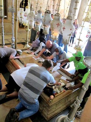 RITUALE: Personlige eiendeler finner veien opp av vesker og sekker f�r de gnis mot steinen der Jesus ble vasket og lagt i likklede etter at han ble tatt ned fra korset. Foto: PETTER L�KEN