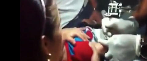 Her holder mora den gr�tende gutten fast mens han blir tatovert