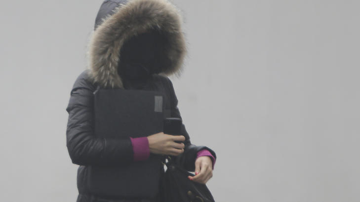 PAKKER SEG INN: De som g� ut i den kinesiske hovedstaden, pakker seg inn. Foto: JASON LEE / REUTERS / NTB SCANPIX