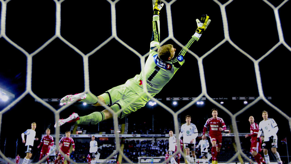NORSK FOTBALL MELLOM STIVE PERMER: Odd-keeper Andre Hansen kaster seg forgjeves etter et skudd fra Rosenborgs Mike Jensen i Skien i serie�pningen for en m�ned siden. Samtidig utkom 15 fotballb�ker om norske toppserieklubber p� Falck Forlag. Foto: Bj�rn Langsem